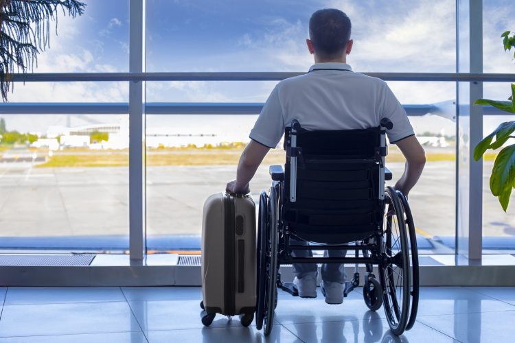 Young man in a wheelchair with luggage at the airport